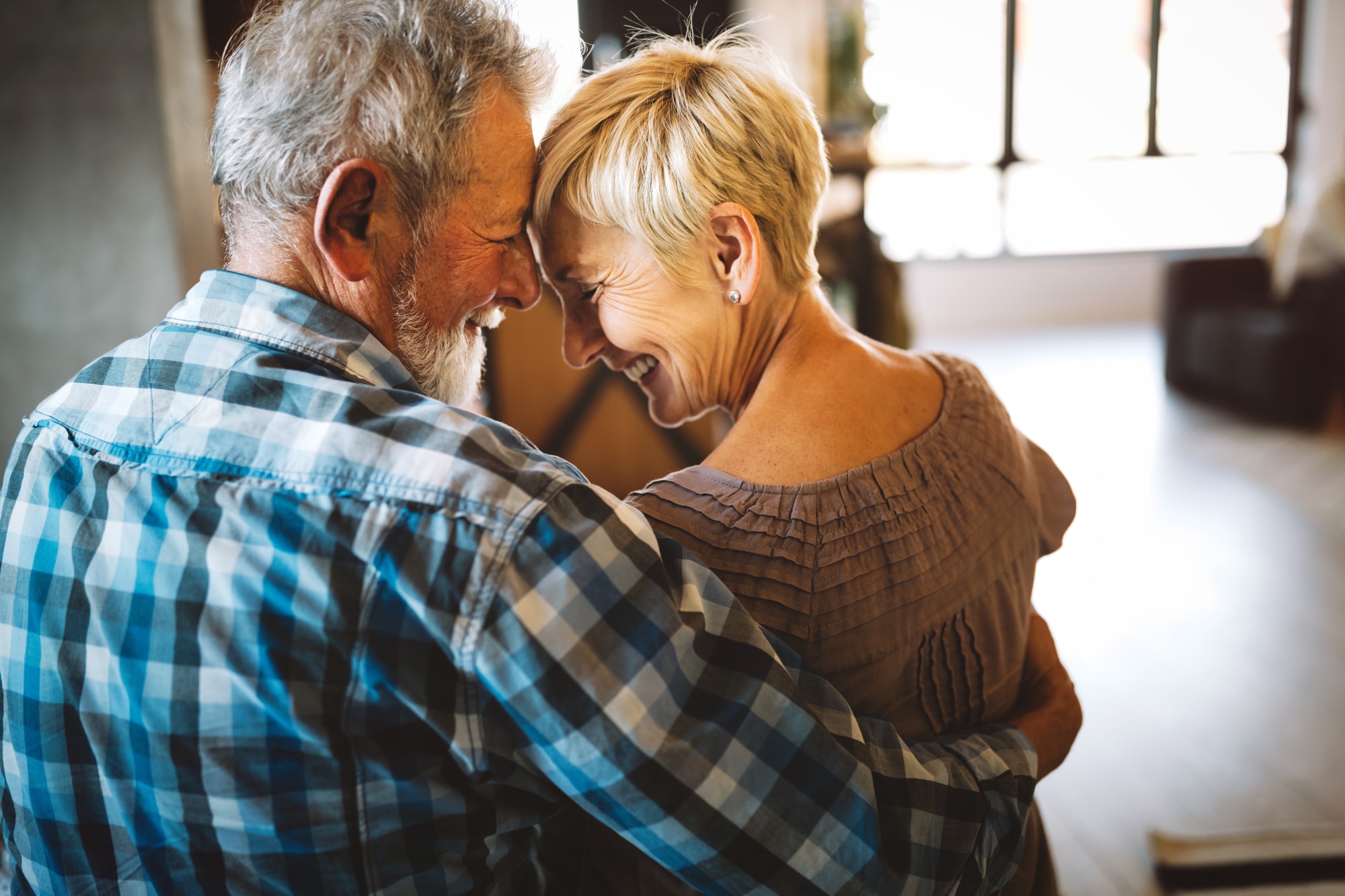 Happy senior couple in love hugging and bonding with true emotions at home Happy smiling senior couple in love hugging and bonding with true emotions at home
